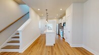 Located at 206 N Leach St in Greenville, SC, this thoughtfully designed three-story home offers three bedrooms and five bathrooms across a well-organized layout. The ground floor includes a garage with a dedicated utility area housing mechanical systems, providing practical functionality from the moment you enter.

The main living level serves as the heart of the home, featuring an open-plan kitchen and dining area that exudes a clean, contemporary aesthetic. The kitchen is appointed with white shaker-style cabinetry, a classic subway tile backsplash, stainless steel appliances, and a central island with a quartz countertop and built-in sink — all illuminated by stylish pendant lighting. Warm hardwood flooring flows throughout this level, complemented by recessed lighting and a bright, airy atmosphere. A convenient half bath with a pedestal sink and natural light rounds out this floor.

The upper levels house the three bedrooms, each finished with plush carpeting, ceiling fans, and windows that invite natural light. The bedrooms are served by well-appointed bathrooms featuring tile flooring, white vanities, and clean, modern fixtures. Multiple closets are distributed throughout the home, offering generous storage. A dedicated laundry room and pantry add further everyday convenience to this efficiently designed residence.