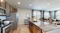 This single-floor residence offers a thoughtfully designed open-concept layout that seamlessly connects the kitchen, dining, and living areas. The kitchen is a standout feature, showcasing dark espresso cabinetry, granite countertops, stainless steel appliances including a refrigerator and range, a subway tile backsplash, and a large center island with an undermount sink and brushed gold faucet. Light wood-style flooring flows throughout, enhancing the bright, airy atmosphere created by abundant natural light from multiple windows dressed with elegant drape panels and shuttered blinds.

The adjoining dining area accommodates a round table with ample space, while the living room offers a comfortable, inviting layout with a ceiling fan, large windows, and views of the outdoors. The bedrooms are generously proportioned, each featuring ceiling fans, large windows, and wood-style flooring, providing a calm and restful environment. The primary bedroom connects to an en-suite bathroom equipped with granite-topped dark cabinetry vanity and access to a walk-in closet. A full bathroom features white subway tile surrounding a soaking tub and shower combination, complemented by matching granite vanity finishes, maintaining a consistent and cohesive design aesthetic throughout the residence.