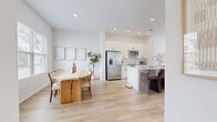 Located in Austin's 78736 zip code, this well-designed two-story home offers 3 bedrooms and 4 bathrooms across two thoughtfully laid-out floors. The main level features an open-concept living, kitchen, and dining area bathed in natural light from large windows with neighborhood views. The kitchen is outfitted with white shaker cabinetry, a subway tile backsplash, stainless steel appliances, a deep single-basin sink, and a spacious island with bar seating — flowing seamlessly into the bright living room, which features light wood flooring, high ceilings, and a ceiling fan. The adjacent dining area provides a comfortable space with continued natural light and outdoor views. Upstairs, the primary bedroom is generously sized with vaulted ceilings, a triple window bank, and a dedicated en-suite bathroom featuring a double vanity and a glass-enclosed walk-in shower. Additional bedrooms are well-proportioned with carpeted floors and ample natural light. Secondary bathrooms are clean and modern, with white tile surrounds and warm wood-tone flooring. A staircase connects both floors, and a hallway and closet add functional storage throughout.