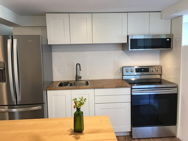 New kitchen with full size fridge, microwave and stove. Additional storage space in island and a large pantry closet near dining area. - 2415 E 12th St