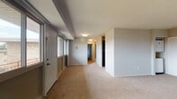This single-floor residence offers a practical and comfortable layout with a clear, logical flow between its key living areas. The entryway welcomes you with large windows that frame outdoor views and fill the space with natural light, opening into a generously sized living area finished with warm beige carpeting and neutral gray walls that lend a clean, understated aesthetic throughout.

The kitchen is equipped with rich dark espresso cabinetry, light granite-style countertops, a stainless steel sink, and black appliances including a full-size refrigerator. Stone-look tile flooring grounds the kitchen space and provides a durable, easy-to-maintain surface. A dedicated utility area accommodates a stacked washer and dryer, adding convenient in-unit laundry access off the main living zone.

Two carpeted bedrooms each feature window blinds that allow for natural light and outdoor views, with neutral walls and ample floor space suitable for a variety of furniture configurations. The full bathroom includes a tiled tub-shower combination, a toilet, and tile flooring in a coordinating stone tone, maintaining the consistent neutral palette found throughout the unit.

The overall layout, as seen in the 3D floorplan, is compact yet efficient, with a central hallway connecting all rooms seamlessly for easy navigation and functional everyday living.