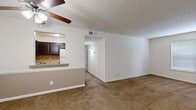 Located at 1706 W Creek Way in Lyndon, Kentucky, this single-floor, one-bedroom, one-bathroom unit offers a well-organized and efficient layout. The living area is carpeted and anchored by a ceiling fan with a light fixture, providing comfort and air circulation. A two-tone wall treatment — with a lighter upper half and a neutral lower half — adds visual interest to the space. A pass-through window with a countertop bar connects the living area to the kitchen, creating an open, communicative feel between the two spaces. The kitchen features dark espresso cabinetry, tile backsplash, light tile flooring, and white appliances including a refrigerator, electric range, and sink. A hallway connects the main living area to the private quarters. The spacious bedroom is highlighted by a cool blue-grey accent wall, plush carpeting, a ceiling fan, a window for natural light, and two mirrored sliding-door closets offering generous storage. The bathroom is clean and functional, featuring a full tiled tub-shower combination, a toilet, and a towel rack. Throughout the unit, a textured ceiling and neutral color palette create a cohesive, understated ambiance suitable for everyday living.