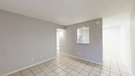 This single-story home offers a practical and efficient layout across three bedrooms and two bathrooms. Light-toned ceramic tile flooring runs consistently throughout the entire home, lending a cohesive and easy-to-maintain aesthetic. The combined kitchen and living room serves as the central hub of the home, with a pass-through window connecting the kitchen to the living area and allowing natural light to flow between spaces. A front-facing window in the living room brings in additional daylight and provides a view of the surrounding neighborhood. The kitchen features white cabinetry and standard appliances. Each of the three bedrooms is a well-proportioned space finished with the same tile flooring and fitted with ceiling fans with integrated lighting, providing both comfort and functionality. The primary bedroom offers a comfortable footprint with ample room for standard furnishings. The two bathrooms are finished in clean white tones, with one featuring a vanity with white cabinetry and a tub/shower combination. A hallway connects the private areas of the home, and a dedicated closet provides additional storage. Textured ceilings are present in select areas, adding subtle dimension to the otherwise clean, neutral interior palette throughout.