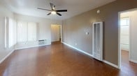 This single-floor residence offers a practical and comfortable layout designed for everyday living. The open living area is anchored by rich hardwood-style flooring and a ceiling fan, creating a bright and airy atmosphere enhanced by natural light streaming through vertical-blind windows. The space flows seamlessly toward the kitchen, which is efficiently arranged in an L-shaped configuration. The kitchen features granite-patterned countertops, white cabinetry offering ample storage, a stainless steel gas range with overhead ventilation, a double-basin stainless steel sink, and wood-style flooring that ties the space together cohesively. A second living or common area provides additional flexible space, also featuring hardwood-style floors, a ceiling fan, and built-in wall heating and cooling units. The bedrooms are well-proportioned, each outfitted with plush wall-to-wall carpet, ceiling fans with light fixtures, and large windows with vertical blinds that invite natural light while maintaining privacy. The bathroom is clean and functional, showcasing a tub and shower combination enclosed by sliding glass doors, a single-sink vanity, and wood-style tile flooring. Throughout the residence, neutral wall tones and consistent finishes create a cohesive, move-in-ready environment.