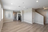 This two-story home in Westminster, California offers three bedrooms and three bathrooms across two well-proportioned floors. The main level features an open-concept living room and kitchen layout, finished with light wood-tone flooring and recessed lighting that keeps the space bright and welcoming. The kitchen is thoughtfully designed with two-tone cabinetry — white uppers and slate-blue lowers — paired with quartz countertops, stainless steel appliances including a French door refrigerator and gas range, and a window above the sink that brings in natural light. The living area flows seamlessly from the kitchen, providing an airy, functional common space. A hallway and a bathroom are also conveniently located on the main floor. Upstairs, three bedrooms offer comfortable proportions, each finished with the same light hardwood-style flooring and neutral warm-beige walls. The bedrooms feature windows with views of the surrounding neighborhood, filling each room with natural light. The primary bedroom provides a generous amount of space. Two additional bathrooms serve the upper level, including one with a sliding glass shower-tub combo. Clean lines, consistent neutral tones, and modern fixtures give the entire home a fresh, move-in-ready feel.