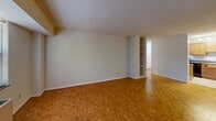 Located at 740 Smallwood Dr in Raleigh, NC, this single-floor residence offers two bedrooms, two bathrooms, and a thoughtfully laid-out floor plan. Distinctive parquet wood flooring runs throughout the main living areas and bedrooms, lending a warm, classic character to the space. The open combined dining and living room is generously sized, featuring textured ceilings and built-in shelving that adds both function and visual interest. Natural light filters in through multiple windows, offering pleasant views of surrounding greenery. The kitchen is well-appointed with warm wood cabinetry, dark laminate countertops, a double-basin sink, black appliances including a range and dishwasher, and track lighting overhead. Light tile flooring grounds the kitchen area. The primary bedroom is spacious, benefiting from multiple windows that frame leafy outdoor views, while the second bedroom includes a large built-in closet for convenient storage. With six closets total throughout the unit, storage is plentiful. Both bathrooms are finished with white tile surrounds, tub-shower combinations, medicine cabinet mirrors, and warm wood vanities with light countertops. A connecting hallway ties the layout together efficiently, creating a comfortable and functional living environment.