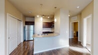 Located at 1721 Memory Lane in McKinney, Texas, this single-story residence presents a clean, functional layout with a neutral color palette and a mix of finishes throughout. The entryway opens into a spacious living area highlighted by rich, dark hardwood flooring that extends through the main living spaces. A ceiling fan overhead and windows fitted with blinds allow for natural light while maintaining privacy, creating a bright and comfortable atmosphere.

The kitchen serves as a central feature of the home, designed with an open peninsula layout that connects seamlessly to the living area. Dark espresso cabinetry pairs with granite countertops and a full suite of stainless steel appliances, including a refrigerator, range, microwave, and dishwasher. Pendant lighting and track lighting illuminate the workspace, adding both style and practicality to the area.

The bedrooms offer a contrast in flooring, transitioning to plush carpet that adds warmth and comfort. Each room features large windows that bring in ample natural light and provide views of the surroundings. The bathroom includes a tiled tub and shower combination with wood-look flooring, maintaining a cohesive aesthetic throughout the home. Overall, the space presents a well-appointed, move-in ready environment suited for comfortable everyday living.