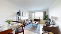 Located at 1203 Maritime Way in Ottawa, this well-appointed one-bedroom, one-bathroom unit offers a thoughtfully designed layout across a single floor. The open-concept living and dining area is anchored by light hardwood flooring and large windows that flood the space with natural light while framing pleasant outdoor views of the surrounding greenery. The kitchen is outfitted with warm maple cabinetry, granite countertops, a tiled backsplash, and a full suite of stainless steel appliances, including a refrigerator, stove, and built-in microwave. A breakfast bar provides a casual dining option alongside the dedicated dining area. French-style glass doors line the hallway, adding an elegant touch while allowing light to pass through the unit. The bedroom offers comfortable carpeted flooring, a generous footprint, and sliding glass doors that open onto a private balcony with open views — a standout feature of the space. The bathroom is finished with large-format tile flooring, a white vanity with a wood-topped counter, a wide mirror, and warm overhead lighting. A separate living room provides additional flexible space for relaxing or working. Clean white walls and neutral tones throughout create a bright, calm, and cohesive ambiance.