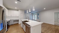 This single-floor residence on Nexus Ave in Stafford, TX offers a thoughtfully designed open-concept layout with clean, modern finishes throughout. The kitchen serves as the centerpiece of the living area, featuring a large white quartz island with an undermount sink, white shaker cabinetry, stainless steel appliances, and pendant lighting overhead. The kitchen flows seamlessly into the living room, which receives natural light through French doors and is equipped with a ceiling fan.

Both bedrooms are well-proportioned, with the primary bedroom featuring plush carpet, a ceiling fan, and direct access to a dedicated bathroom and walk-in closet. The primary bathroom is outfitted with an extended double-sink vanity, white quartz countertops, LED-backlit mirrors, and wood-look flooring. The walk-in closet includes built-in shelving and double hanging rods for ample storage. The second bedroom also features carpet flooring and connects to its own bathroom with matching modern finishes.

A dedicated laundry area with full-size washer and dryer hookups and overhead cabinetry adds functional convenience. Wood-look flooring runs throughout the main living areas, tying together the bright, contemporary aesthetic of this well-appointed residence.