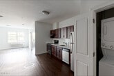 Located at 747 Grand St in Jersey City, NJ, this one-bedroom, one-bathroom residence offers a well-designed single-floor layout with a practical and modern finish throughout. Rich hardwood flooring flows consistently across the living areas and bedroom, creating a warm and cohesive aesthetic.

The kitchen is a standout feature, outfitted with deep mahogany-toned cabinetry, white quartz countertops, a classic subway tile backsplash, and a full suite of stainless steel appliances including a refrigerator, dishwasher, electric range, and under-cabinet range hood. A dedicated laundry closet with a stacked washer and dryer unit adds significant convenience.

The living area is open and bright, with clean white walls and ample space for comfortable furnishing arrangements. The bedroom is generously proportioned, offering a quiet retreat with a window providing views of the surrounding neighborhood streetscape and a wall-mounted HVAC unit for climate control.

The bathroom includes a full soaking tub with a subway-tiled shower surround, complemented by classic fixtures. Throughout the unit, white panel doors and crisp trim work contribute to a clean, contemporary feel, making this a functional and well-appointed residence in Jersey City.