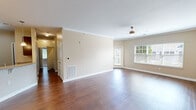 Located at 7300 Sir Walter Way in Knoxville, Tennessee, this well-appointed single-story home offers three bedrooms and two bathrooms across a generous, efficiently designed floor plan. The expansive living room serves as the heart of the home, featuring rich hardwood flooring, elegant crown molding, a ceiling fan, and large windows that fill the space with natural light. The open layout flows seamlessly into a dining area and a kitchen outfitted with dark cabinetry, stainless steel appliances, and a breakfast bar with pendant lighting overhead. The primary bedroom is a comfortable retreat complete with plush carpeting, a ceiling fan, a walk-in closet with wire shelving, and a private en-suite bathroom featuring a framed glass-door shower and a dark-cabinet vanity with a light countertop. Two additional bedrooms mirror the same warm carpet tones and ceiling fans, each with windows offering outdoor views. The second bathroom is well-sized, offering a tub-shower combination, a matching dark vanity, and light tile flooring. A hallway connects the living areas to the bedrooms, keeping the layout practical and cohesive. Throughout the home, neutral warm-beige walls create a clean, versatile backdrop suited to a variety of styles.