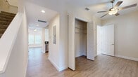 This two-story residence is thoughtfully designed to maximize functionality and comfort across its well-proportioned layout. The main level features an open-plan kitchen and living area, where the kitchen stands out with crisp white shaker cabinetry, granite countertops, a classic subway tile backsplash, and a full suite of stainless steel appliances. Light hardwood-style flooring flows throughout the main living areas, complemented by neutral warm-toned walls and ceiling fans that enhance the bright, airy atmosphere. Multiple windows fitted with white blinds allow for abundant natural light throughout. The upper floor houses the spacious primary bedroom, finished with plush carpeting, natural light from dual windows, and access to a generously sized walk-in closet outfitted with extensive wire shelving and hanging systems. The four bathrooms are finished with light tile flooring, white vanities, and glass-enclosed walk-in showers featuring white subway tile and decorative mosaic accents. Two dedicated laundry areas provide exceptional convenience, each with hardwood-style flooring and built-in shelving. Additional hallways and closets on both floors contribute to the home's notable storage capacity, while a connecting staircase links the two levels seamlessly.