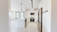 Located at 32888 Maclure Rd in Abbotsford, BC, this well-designed two-bedroom, two-bathroom unit offers a thoughtful layout with modern finishes across a single floor. The entrance opens into a bright, open-concept living and kitchen area finished with light hardwood-style flooring. The kitchen is a standout feature, boasting flat-panel white cabinetry, stainless steel appliances including a refrigerator, electric range, and built-in microwave, complemented by a subway tile backsplash and a central island with an undermount sink and pendant lighting above. The spacious living area is bathed in natural light through large windows and a sliding glass door that leads to a private balcony with outdoor views of the surrounding neighbourhood and greenery. The generously sized primary bedroom features plush carpeting and a large window overlooking trees, while the second bedroom also offers carpet flooring and a bright window with neighbourhood views and a built-in closet. The ensuite bathroom includes a glass-enclosed shower with tile surround, a white floating vanity, and large-format tile flooring. The second bathroom features a full soaker tub with shower, a matching white vanity, and tile flooring, maintaining a clean, contemporary aesthetic throughout.