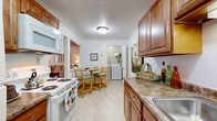 Located in Westlake, Ohio, this single-floor, 2-bedroom, 2-bathroom residence offers a thoughtfully designed layout with comfortable living spaces throughout. The living room is highlighted by large sliding glass doors that invite abundant natural light and provide views of the outdoors, with plush carpeting and a textured ceiling adding warmth to the space. Adjacent to the living room, the dining area features a ceiling fan, chair rail molding, and continued access to the sliding glass doors, creating a seamless connection between the two spaces. The galley-style kitchen is equipped with warm wood cabinetry, granite-style countertops, white appliances including a range, microwave, and refrigerator, and easy-care flooring. A dedicated laundry room houses a full-size washer and dryer with overhead shelving for added storage. The spacious primary bedroom offers generous proportions with soft carpeting and neutral walls. The second bedroom provides flexible use as a guest room or home office. Both bathrooms are finished with tile flooring, wood vanities, and well-lit mirrors. The overall ambiance is bright, clean, and move-in ready, offering a practical and comfortable living environment.