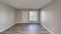 Located at 2404 Hill St in Raleigh, NC, this single-floor residence offers three bedrooms and two full bathrooms within a well-organized layout. The open-concept kitchen and living area serves as the heart of the home, featuring white cabinetry with ample storage, light-toned countertops, a double-basin sink, and appliances including a refrigerator, electric range, and dishwasher. Wood-look plank flooring runs throughout the main living areas, lending a clean and cohesive look, while neutral gray walls create a versatile backdrop throughout. The living room benefits from natural light through a front-facing window and provides direct access to the entry door. A connecting hallway links the main living space to all three bedrooms, each finished with soft carpeting and neutral walls. The primary bedroom offers a comfortable footprint with a closet. Both bathrooms are functional and cleanly finished, each featuring a full tub-shower combo with white surround, a vanity with under-sink storage, and wood-look tile flooring. The textured ceilings and consistent neutral palette throughout contribute to a tidy, move-in-ready atmosphere suited for a variety of living arrangements.