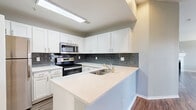 Located at 2652 S Moore Dr in Lakewood, Colorado, this single-floor, 3-bedroom, 2-bathroom home offers a well-designed layout across a comfortable footprint. The open-concept kitchen is a standout feature, showcasing crisp white shaker cabinetry, a slate-toned subway tile backsplash, quartz countertops, a peninsula with an undermount sink, and a full suite of stainless steel appliances including a range, microwave, and refrigerator. Wood-look plank flooring flows throughout the main living areas, connecting the kitchen seamlessly to the living room, which is anchored by a classic fireplace with a white mantle and brightened by large windows that invite natural light. A sliding glass door leads to a private balcony. The three bedrooms feature plush carpeting and windows with exterior views, with the primary bedroom offering a generous layout. Both bathrooms are finished with white vanity cabinetry, well-lit mirrors, and tub-shower combinations with tile surrounds. A dedicated in-unit laundry room with washer and dryer provides added convenience. Four closets offer ample storage throughout the home, and a hallway connects all areas efficiently. The neutral color palette and modern finishes give the space a clean, move-in-ready aesthetic.