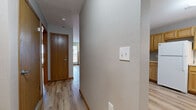 Located at 97 SW Rose Hill Cir in Topeka, Kansas, this single-floor, two-bedroom, two-bathroom home offers a clean and functional layout finished with consistent light wood luxury vinyl plank flooring throughout. The living room serves as the heart of the home, featuring a tiled fireplace flanked by two windows that invite natural light and provide views of the surrounding neighborhood. The kitchen is outfitted with warm honey-toned wood cabinetry, a dishwasher, a sink, and ample counter space, with an open sightline connecting it to the hallway and main living areas. A central hallway with warm wood-trimmed doors links all rooms with ease. The primary bedroom is generously sized and includes two closets — one walk-in — offering notable storage capacity. The second bedroom is comfortably proportioned with its own closet access. Both bathrooms feature wood-toned vanities and light wood flooring; one includes a walk-in shower with built-in shelving, while the other offers a full tub-shower combo. Neutral gray walls and warm wood baseboards create a cohesive, understated aesthetic throughout the home, making it a versatile and move-in ready space.