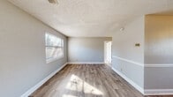 Located at 254 Fox Trace in Augusta, Georgia, this single-story, 2-bedroom, 1-bathroom home offers a practical and straightforward layout across a compact footprint. The interior is connected by a central hallway that links all principal rooms, promoting an efficient flow throughout the home.

The living room greets residents at the front entry, featuring wood-look plank flooring, neutral gray walls, white baseboards, and a textured ceiling. Natural light filters in through windows fitted with horizontal blinds, creating a bright and open atmosphere. The kitchen is positioned toward the rear and is equipped with warm-toned wood cabinetry, an electric range, a single-basin sink, and wood-look flooring that mirrors the living area, with a window and exterior door providing additional natural light and ventilation.

Both bedrooms are finished with neutral carpet and light gray walls, each receiving natural light through multiple windows. The primary bedroom offers a comfortable and functional footprint. The shared full bathroom includes a tub-shower combination with white tile surround, a toilet, and a window for natural light and airflow. Throughout the home, consistent neutral finishes and wood-look flooring provide a cohesive and clean aesthetic.