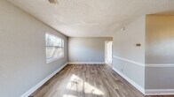 Located at 254 Fox Trace in Augusta, Georgia, this single-story, 2-bedroom, 1-bathroom home offers a practical and straightforward layout across a compact footprint. The interior is connected by a central hallway that links all principal rooms, promoting an efficient flow throughout the home.

The living room greets residents at the front entry, featuring wood-look plank flooring, neutral gray walls, white baseboards, and a textured ceiling. Natural light filters in through windows fitted with horizontal blinds, creating a bright and open atmosphere. The kitchen is positioned toward the rear and is equipped with warm-toned wood cabinetry, an electric range, a single-basin sink, and wood-look flooring that mirrors the living area, with a window and exterior door providing additional natural light and ventilation.

Both bedrooms are finished with neutral carpet and light gray walls, each receiving natural light through multiple windows. The primary bedroom offers a comfortable and functional footprint. The shared full bathroom includes a tub-shower combination with white tile surround, a toilet, and a window for natural light and airflow. Throughout the home, consistent neutral finishes and wood-look flooring provide a cohesive and clean aesthetic.