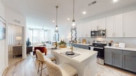 Located at 1290 Old Peachtree Rd NW in Duluth, Georgia, this thoughtfully designed single-floor residence offers a seamless blend of modern style and everyday functionality. The open-concept layout connects the kitchen, dining, and living areas into one cohesive, light-filled space.

The kitchen is a standout feature, showcasing a two-tone design with crisp white upper cabinets and slate-gray lower cabinetry, all accented with brushed gold hardware. A classic white subway tile backsplash complements the quartz countertops, while stainless steel appliances — including a range, microwave, and French door refrigerator — provide a polished, contemporary look. A central island with seating and elegant pendant lighting serves as both a functional workspace and a social hub.

The living area is generously sized, featuring large windows with blinds that invite abundant natural light, and a ceiling fan overhead. Wood-look flooring flows throughout the main living spaces, adding warmth and continuity.

The bedrooms are carpeted and serene, each benefiting from large windows that fill the rooms with natural light. The primary bedroom connects to a well-designed bathroom featuring gray cabinetry, quartz countertops, a walk-in shower with tile surround, and wood-look flooring. The overall ambiance throughout is clean, bright, and contemporary.