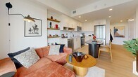 This 190 square foot apartment in New Westminster, BC, exemplifies efficient urban living. The space is thoughtfully designed to maximize functionality within its compact footprint. The bedroom area features a large window providing ample natural light and city views. A modern black shelving unit offers both storage and display space, complementing the room's contemporary aesthetic.

The bathroom, though small, is well-appointed with a full-sized bathtub, modern fixtures, and a clean, neutral color palette. Light wood accents add warmth to the space.

The main living area combines the kitchen and living room in an open-concept layout. The kitchen boasts sleek white cabinetry, stainless steel appliances, and wooden open shelving. A small dining island with seating serves as a transition to the living space, which is anchored by a comfortable coral-colored sectional sofa.

Throughout the apartment, large windows flood the space with natural light, creating an airy atmosphere despite the limited square footage. The cohesive design aesthetic, featuring a mix of modern and mid-century elements, unifies the space and enhances its visual appeal.