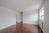 Located at 1309 Wilson Avenue in Toronto's Wilson Heights neighbourhood, this 2-bedroom, 1-bathroom unit offers a practical and well-laid-out single-floor plan. Throughout the unit, warm-toned parquet hardwood flooring adds a classic character, complemented by light grey walls and clean white trim.

The open living and dining area is generously proportioned, featuring multiple windows that bring in ample natural light and views of the surrounding neighbourhood. Cast-iron and panel radiators provide efficient heating throughout the unit. The kitchen is efficiently designed with white cabinetry, stainless steel appliances including a full-size refrigerator, microwave, and range, along with tile flooring that transitions seamlessly from the main living areas.

Both bedrooms are well-sized, each with windows offering city views and individual radiator heating. The primary bedroom includes a mirrored sliding closet, adding both storage and a sense of space. The second bedroom also benefits from natural light through a dedicated window.

The bathroom is finished with full white tile surround, a soaker tub with overhead shower, a mosaic tile accent border, and a pedestal sink, creating a clean and functional space. A hallway connects all rooms, providing a cohesive and organized flow throughout the unit.