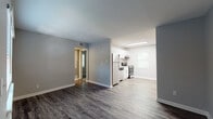Located at 743 Holmes St NW in Atlanta, GA 30318, this single-floor unit offers a clean, modern aesthetic throughout. The open-concept living and kitchen area is finished with durable hardwood-style flooring in a rich, dark tone, complemented by neutral gray walls and crisp white trim. The kitchen is well-appointed with stainless steel appliances — including a refrigerator, dishwasher, and electric range — paired with white shaker-style cabinetry, light granite countertops, and a tile backsplash. A window above the sink allows natural light to brighten the space. The living area is spacious and flows seamlessly from the kitchen, providing a versatile layout for everyday living. The primary bedroom features dark hardwood-style flooring, a large window with blinds, and access to a walk-in closet. An additional bedroom is carpeted and receives natural light through a window with blinds, offering a comfortable and quiet retreat. The bathroom is fitted with a full tub-shower combo with a clean white surround and built-in shelving niches. Throughout the unit, consistent gray tones and modern finishes create a cohesive and move-in-ready atmosphere.