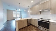 Located at 165 Belmont Ave in Belleville, NJ, this modern single-floor residence showcases a thoughtfully designed interior with a cohesive contemporary aesthetic throughout. Rich hardwood-style flooring flows seamlessly across all areas, grounding the space with warmth and continuity.

The open-concept kitchen serves as the heart of the unit, featuring a large peninsula with a crisp white quartz countertop, an integrated sink, and pendant lighting that adds both function and style. Light wood-grain cabinetry lines the walls alongside a classic white subway tile backsplash, while stainless steel appliances — including a range, dishwasher, refrigerator, and microwave — complete the modern culinary setup. The kitchen opens directly into the living area, which benefits from natural light and includes a ceiling fan overhead.

The bedroom offers a calm, neutral palette with warm beige walls, large windows that frame views of the surrounding Belleville streetscape, and a ceiling fan for year-round comfort. An additional room with clean white walls and a panel door provides flexible living or storage space.

The bathroom is well-appointed with a wood-toned floating vanity, a large mirror, bright vanity lighting, a soaking tub with tiled surround, and matching hardwood-style flooring, maintaining the unit's consistent modern design language throughout.