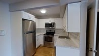 Located at 1680 Pelham Parkway S in the Bronx, this single-floor residence offers a thoughtfully updated living space with modern finishes throughout. The kitchen stands out as a central highlight, showcasing crisp white shaker-style cabinetry that provides generous storage from floor to ceiling. Stainless steel appliances — including a full-size refrigerator, electric range, and over-the-range microwave — lend the kitchen a clean, contemporary feel. Marble-look countertops complement the classic white subway tile backsplash, adding a timeless yet stylish touch to the cooking space. A stainless steel sink sits neatly beneath the counter, completing the functional layout. Warm hardwood flooring runs through the kitchen, adding a welcoming contrast to the bright cabinetry and light-toned surfaces. Flush ceiling lighting ensures the space is well-illuminated. The overall design reflects a careful balance of practicality and modern aesthetics, making this residence a comfortable and visually appealing home in the Pelham Parkway neighborhood of the Bronx — a well-established area known for its proximity to Pelham Bay Park and convenient access to public transportation.