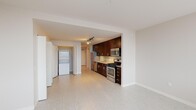 This single-floor apartment at 150 Forest Ave in Oak Park, IL offers a clean, modern aesthetic throughout. The open-concept kitchen is a standout, featuring rich dark-wood cabinetry, granite countertops, a tile backsplash, and a full suite of stainless steel appliances including a gas range, microwave, dishwasher, and refrigerator. Track lighting illuminates the space efficiently. The living area is bright and open, with light-toned tile flooring that extends throughout. A dedicated laundry area includes a stacked washer and dryer alongside generous closet space. The bathroom is finished with granite counters and large-format floor tiles.