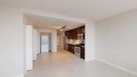 This single-floor apartment at 150 Forest Ave in Oak Park, IL offers a clean, modern aesthetic throughout. The open-concept kitchen is a standout, featuring rich dark-wood cabinetry, granite countertops, a tile backsplash, and a full suite of stainless steel appliances including a gas range, microwave, dishwasher, and refrigerator. Track lighting illuminates the space efficiently. The living area is bright and open, with light-toned tile flooring that extends throughout. A dedicated laundry area includes a stacked washer and dryer alongside generous closet space. The bathroom is finished with granite counters and large-format floor tiles.