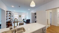 Located at 95 Main St in Hartford, Connecticut, this single-floor residence offers a thoughtfully designed open-concept layout with clean, contemporary finishes throughout. Light-toned hardwood flooring flows seamlessly across every room, creating a cohesive and inviting atmosphere.

The kitchen is well-appointed with stainless steel appliances, including a French door refrigerator and electric range, complemented by gray shaker-style cabinetry and a white quartz countertop with an undermount sink. A pendant light fixture anchors the space, which opens directly into the living area for easy interaction between rooms.

The living area is bright and airy, featuring multiple windows that bring in generous natural light and views of the surrounding Hartford streetscape. Recessed lighting adds to the well-lit ambiance throughout the main living space.

The bedrooms are comfortably proportioned, each featuring large windows with roller shades that provide both light control and privacy. The layout also includes an in-unit stacked washer and dryer, adding practical convenience.

Two bathrooms serve the residence: one features a tiled tub-shower combination, while the other offers a glass-enclosed walk-in shower. Both are finished with gray vanity cabinetry, white quartz countertops, and coordinating tile work, maintaining a consistent modern aesthetic throughout.