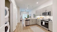 Located at 930 Ridgeview Dr in Allen, TX, this well-appointed one-bedroom, one-bathroom residence offers a cohesive, modern design across a single floor. The open-concept layout connects the kitchen and living room seamlessly, creating an airy, functional living space bathed in natural light from large windows.

The kitchen is a standout feature, showcasing gray shaker-style cabinetry with matte black hardware, light granite countertops, a white subway tile backsplash, and a full suite of stainless steel appliances, including a range, over-the-range microwave, dishwasher, and refrigerator. Elegant pendant lights hang above the peninsula, enhancing both style and utility. Light wood-look flooring runs throughout the main living areas, adding warmth and continuity.

The living room is bright and inviting, with natural light filtering through slatted window blinds and a ceiling fan overhead.

The bedroom offers a tranquil retreat, featuring plush carpet, a large window, and direct access to the full bathroom. The bathroom is finished with granite countertops, gray shaker vanity cabinetry, and wood-look flooring, complementing the overall design palette.

A generously sized walk-in closet with dual hanging rods and shelving provides excellent storage. A dedicated closet houses a stacked full-size washer and dryer, alongside a built-in pantry with open shelving — a practical and convenient amenity.