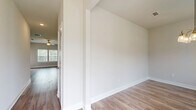 Located at 2300 Paris Rd in Dallas, GA, this two-story home offers a thoughtfully designed layout spread across two floors. The main level features an open-concept kitchen and living area anchored by a large center island with granite countertops, white shaker cabinets, stainless steel appliances, and warm wood-look flooring. A dedicated dining room is highlighted by an elegant multi-bulb chandelier and generous natural light from a side window. The living room opens to a staircase with a classic wood-and-iron railing, adding architectural character to the space. A dedicated laundry room with full-size washer and dryer hookups adds everyday convenience, and the attached two-car garage provides ample storage and parking. Upstairs, four bedrooms include a generously sized primary suite complete with a walk-in closet featuring built-in wire shelving and vaulted ceiling details. The primary bathroom offers a dual-sink vanity with granite countertops and white cabinetry. Additional bedrooms feature ceiling fans, vaulted ceilings, and natural light. Three full bathrooms serve the home throughout. Consistent wood-look flooring, neutral wall tones, and clean white trim unify the interior with a fresh, modern aesthetic.