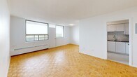 Located on the 8th floor at 30 High St E in Mississauga, this 2-bedroom, 1-bathroom unit offers a well-organized layout across a single floor. Warm parquet flooring runs throughout the living areas and bedrooms, lending a classic character to the clean, modern aesthetic.

The open living area is bright and airy, benefiting from large floor-to-ceiling windows that fill the space with natural light and provide expansive views of the surrounding cityscape and greenery. Baseboard heating units are positioned beneath the windows throughout.

The kitchen is thoughtfully updated with white cabinetry, subway tile backsplash, dark countertops, and stainless steel appliances including a refrigerator, stove, and built-in microwave. Light tile flooring completes the contemporary look.

Both bedrooms are generously proportioned, with the primary bedroom offering ample space and a large sliding-door closet for storage. Each bedroom features a window with outdoor views and baseboard heating. The second bedroom also includes a sliding-door closet.

The bathroom is finished with crisp white subway tile surrounding a full soaker tub and shower combination, accented with chrome fixtures for a clean, timeless look. A hallway connects all rooms, contributing to a functional and efficient floor plan throughout this well-appointed unit.
