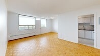 Located on the 8th floor at 30 High St E in Mississauga, this 2-bedroom, 1-bathroom unit offers a well-organized layout across a single floor. Warm parquet flooring runs throughout the living areas and bedrooms, lending a classic character to the clean, modern aesthetic.

The open living area is bright and airy, benefiting from large floor-to-ceiling windows that fill the space with natural light and provide expansive views of the surrounding cityscape and greenery. Baseboard heating units are positioned beneath the windows throughout.

The kitchen is thoughtfully updated with white cabinetry, subway tile backsplash, dark countertops, and stainless steel appliances including a refrigerator, stove, and built-in microwave. Light tile flooring completes the contemporary look.

Both bedrooms are generously proportioned, with the primary bedroom offering ample space and a large sliding-door closet for storage. Each bedroom features a window with outdoor views and baseboard heating. The second bedroom also includes a sliding-door closet.

The bathroom is finished with crisp white subway tile surrounding a full soaker tub and shower combination, accented with chrome fixtures for a clean, timeless look. A hallway connects all rooms, contributing to a functional and efficient floor plan throughout this well-appointed unit.