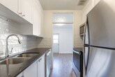 Located at 50 Adelaide Ave E in Oshawa, Ontario, this 2-bedroom, 1-bathroom unit offers a clean, modern aesthetic throughout. Light-toned luxury vinyl plank flooring flows seamlessly across the entire space, complementing the crisp white walls and creating a bright, cohesive interior.

The combined living and dining area is generously sized, featuring a large bank of windows that flood the room with natural light and offer leafy, tree-lined views. Baseboard heating units run beneath the windows, ensuring year-round comfort. A private balcony extends the living space outdoors, providing peaceful views of the surrounding greenery and landscaped grounds.

The galley-style kitchen is thoughtfully designed with white shaker cabinetry, dark quartz countertops, a double stainless steel undermount sink, and a classic white subway tile backsplash. Stainless steel appliances complete the functional layout.

Both bedrooms are well-proportioned and bright. The primary bedroom features a sliding-door closet and a window overlooking mature trees. The second bedroom offers a calm, neutral palette ideal for rest or use as a home office.

The bathroom is finished with full subway tile surrounds, a soaker tub with shower, and chrome fixtures, delivering a clean and timeless look. This thoughtfully updated unit combines practical layout with refined finishes in a serene setting.