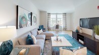 This single-floor residence offers a thoughtfully designed layout that balances open communal spaces with private retreats. The living area serves as the heart of the home, featuring warm hardwood-style flooring, neutral walls, and large windows dressed with patterned curtains that invite generous natural light and outdoor views. The space flows seamlessly, accommodating both a dedicated seating area and a separate workspace near the windows.

The kitchen is well-equipped with dark espresso cabinetry extending to the ceiling, stainless steel appliances including a refrigerator, range, and microwave, and light granite countertops that extend into a breakfast bar with seating. Track lighting overhead enhances both function and ambiance.

Two bedrooms provide comfortable accommodations, each featuring plush carpeting, ceiling fans, and large windows with outdoor views. The primary bedroom includes a bold teal accent wall and ample natural light, while the secondary bedroom maintains a neutral, serene palette.

The full bathroom is finished with white tile, a soaking tub with shower combination, dark vanity cabinetry, and a clean, bright aesthetic throughout. The cohesive teal and neutral color scheme ties the entire residence together.