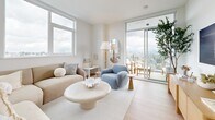 This contemporary 900 square foot apartment in New Westminster, BC, offers a harmonious blend of style and functionality. The space is thoughtfully designed with an open-concept layout, maximizing the use of natural light and space. The living area is a testament to modern aesthetics, featuring a neutral color palette, sleek furniture, and floor-to-ceiling windows that frame panoramic city views.

The kitchen is a highlight, boasting a perfect balance of form and function. It features two-tone cabinetry, with upper white cabinets and lower wood-grain units, complemented by stainless steel appliances and a spacious island with a quartz countertop. The living room seamlessly connects to the kitchen, creating an ideal space for entertaining or relaxing.

Both bedrooms are generously sized, with the primary bedroom measuring 130 square feet. They feature large windows, ample closet space, and are decorated in a calming, neutral palette. The two bathrooms continue the modern theme with sleek fixtures, wood vanities, and a combination of bathtub and walk-in shower options.

Throughout the apartment, light wood flooring adds warmth and continuity. Clever storage solutions and built-in shelving units maximize the available space. The apartment's design emphasizes a clean, uncluttered look while maintaining a cozy and inviting atmosphere. This thoughtfully designed space offers a perfect blend of urban sophistication and comfortable living.