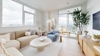 This contemporary 900 square foot apartment in New Westminster, BC, offers a harmonious blend of style and functionality. The space is thoughtfully designed with an open-concept layout, maximizing the use of natural light and space. The living area is a testament to modern aesthetics, featuring a neutral color palette, sleek furniture, and floor-to-ceiling windows that frame panoramic city views.

The kitchen is a highlight, boasting a perfect balance of form and function. It features two-tone cabinetry, with upper white cabinets and lower wood-grain units, complemented by stainless steel appliances and a spacious island with a quartz countertop. The living room seamlessly connects to the kitchen, creating an ideal space for entertaining or relaxing.

Both bedrooms are generously sized, with the primary bedroom measuring 130 square feet. They feature large windows, ample closet space, and are decorated in a calming, neutral palette. The two bathrooms continue the modern theme with sleek fixtures, wood vanities, and a combination of bathtub and walk-in shower options.

Throughout the apartment, light wood flooring adds warmth and continuity. Clever storage solutions and built-in shelving units maximize the available space. The apartment's design emphasizes a clean, uncluttered look while maintaining a cozy and inviting atmosphere. This thoughtfully designed space offers a perfect blend of urban sophistication and comfortable living.