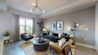 This single-floor residence offers a carefully considered layout that maximizes functionality across its one bedroom and one bathroom. The open-concept living area serves as the centerpiece of the home, featuring warm neutral walls, hardwood-style flooring, and a striking multi-arm chandelier that adds a contemporary focal point. Large windows flood the space with natural light, framing outdoor views and creating a bright, welcoming atmosphere.

The kitchen is a standout feature, outfitted with crisp white shaker cabinetry, quartz countertops, and a bold geometric blue tile backsplash that introduces visual interest. A center island with bar seating provides additional workspace and casual dining, while stainless steel appliances, including a full-size refrigerator, range, microwave, and dishwasher, complete the well-equipped space. Pendant lighting above the island adds a polished finishing touch.

The bedroom is a calm retreat, featuring a window with outdoor views, hardwood-style flooring, and ample natural light filtered through floor-length curtains. The bathroom is elegantly finished with large-format tile flooring, a white vanity with quartz countertops, and a full tub-shower combination surrounded by marble-style tile surround.