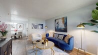 This single-floor residence offers a cohesive and thoughtfully designed layout that balances comfort and style. The living area serves as the heart of the home, featuring warm hardwood-style flooring, soft neutral walls, and a textured ceiling. The space is anchored by bold design accents, including a striking blue velvet sofa, gold-accented furnishings, and large abstract wall art that lends a contemporary, curated feel.

The kitchen is efficiently laid out with white shaker cabinetry, granite-look countertops, and black appliances, including a range and dishwasher. Hardwood-style flooring continues here, adding visual continuity. Adjacent to the kitchen is a cozy dining nook, illuminated by a modern chandelier and adorned with framed abstract artwork, centered around a round marble-top table.

The bedroom is carpeted for comfort and features a ceiling fan, a window with outdoor views, and ample space for furniture arrangement. The room carries the same refined aesthetic seen throughout the home.

The bathroom is finished with large-format gray tile surrounding the soaking tub and shower combination, complemented by wood-look flooring and brushed nickel fixtures, creating a clean and modern atmosphere.

Overall, this residence presents a well-connected, single-level floor plan with consistent, stylish finishes that make it both functional and visually appealing.