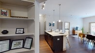 This thoughtfully designed single-floor residence offers a seamless blend of modern style and everyday functionality. The open-concept layout connects the kitchen, dining, and living areas into one cohesive, flowing space anchored by rich dark hardwood flooring throughout.

The kitchen is a standout feature, showcasing dark espresso cabinetry extending to tall ceilings, stainless steel appliances including a refrigerator, range, and microwave, a subway tile backsplash, and light quartz countertops. A central island with pendant lighting above provides generous counter space and bar seating for up to four, making it ideal for both casual meals and entertaining. An adjacent open pantry with built-in shelving adds valuable storage and organization.

The living area benefits from large windows that invite natural light and offer views to the exterior, creating a bright and welcoming atmosphere. Soaring ceilings with track lighting add to the sense of openness.

The bedroom is a calm retreat with plush carpeting, a sizable window for natural light, and ample room for a full furniture arrangement. The bathroom features a wide vanity with quartz countertops, a large mirror, pendant lighting, dark wood cabinetry, and a walk-in glass shower.

A dedicated in-unit laundry closet with front-load washer completes this well-equipped and modern residence.
