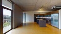 Located at 120 Westlake Avenue, Unit 709 in Seattle's South Lake Union neighborhood, this single-floor residence showcases a refined industrial-modern aesthetic throughout. Warm bamboo hardwood flooring runs continuously across the open living areas, contrasting beautifully with the exposed concrete ceiling that lends the space a distinctly contemporary character.

The expansive living area is bathed in natural light through floor-to-ceiling windows and glass sliding doors that frame views of the surrounding treetops and Seattle skyline, with access to an outdoor balcony. The open-plan layout flows seamlessly into the kitchen, which is outfitted with dark wood flat-front cabinetry, frosted glass upper cabinets, stainless steel appliances including a gas range, built-in oven, microwave, and full-size refrigerator, as well as a spacious central island with a stone-toned countertop.

A glass partition wall elegantly separates the living and sleeping areas, maintaining a sense of openness while defining each zone. The bathroom features large-format tile flooring, a floating dark wood vanity with granite countertop, a wide mirror, and a separate water closet. An in-unit laundry area with a full-size washer and dryer adds everyday convenience. Track lighting throughout complements the architectural details of this thoughtfully designed urban residence.