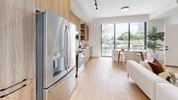 Located on Biscayne Boulevard in Miami, this contemporary 3-story townhouse offers a well-planned multi-level layout with 2 bedrooms, 3 bathrooms, and a private garage. Light wood flooring flows throughout the main living areas, complemented by soaring ceilings and ceiling fans that enhance the airy, open atmosphere. The main floor features a bright, open-plan living room, dining area, and kitchen. The kitchen is outfitted with warm wood cabinetry, stainless steel appliances, and sleek countertops, opening directly to the dining space and a balcony with outdoor views. The living room benefits from floor-to-ceiling windows that flood the space with natural light. A conveniently located half bathroom serves the main floor. Upstairs, the primary bedroom is generously proportioned, featuring large sliding glass doors that lead to a private balcony with scenic views. The en-suite primary bathroom showcases marble-look tile, a double-sink wood vanity with black hardware, and a walk-in glass shower with a rain head. The second bedroom is well-sized with its own closet access. A den provides flexible additional space. The ground level houses the private garage with a patio, completing this thoughtfully designed Miami townhouse.