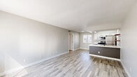 Located at 1829 E Morten Ave in Phoenix, AZ, this two-bedroom, two-bathroom unit offers a clean, modern aesthetic across a single floor. The open-concept living, dining, and kitchen area is anchored by light wood-look flooring that flows throughout, complemented by neutral gray walls and crisp white trim that create a bright, airy atmosphere. Natural light streams in through multiple windows fitted with blinds.

The kitchen is a standout feature, equipped with stainless steel appliances including a range, microwave, and refrigerator. Sleek white upper cabinetry contrasts with gray lower cabinets and white quartz countertops. A peninsula with an undermount sink provides additional prep and dining space, while a decorative geometric tile accent wall with open wooden shelving adds a stylish focal point.

The two bedrooms offer a comfortable retreat, with plush carpeting and windows that bring in natural light. A hallway connects the bedrooms to the two bathrooms, one of which features a tub/shower combination with clean white surrounds and wood-look tile flooring. The layout also includes a dedicated closet for added storage. Overall, the space presents a cohesive, well-maintained interior with contemporary updates throughout.