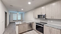 Located at 17448 N Eldridge Parkway in Tomball, Texas, this one-bedroom, one-bathroom residence offers a thoughtfully designed single-floor layout with contemporary finishes throughout. The open-concept kitchen serves as the heart of the home, showcasing light wood-toned cabinetry, granite countertops, and a full suite of stainless steel appliances including a range, built-in microwave, and dishwasher. Light wood-look flooring runs throughout the main living and kitchen areas, contributing to a clean, modern aesthetic. The kitchen flows naturally into the living area, which is brightened by a window with blinds and topped with a ceiling fan for added comfort. The bedroom offers plush carpeting, a ceiling fan with lighting, and a sizable window that allows natural light to fill the space. A dedicated closet provides convenient storage directly off the bedroom. The bathroom is finished with large-format marble-style tile surrounding a soaking tub and shower combination, paired with chrome fixtures for a polished look. Neutral tones and consistent finishes throughout the residence create a cohesive, move-in ready environment well-suited for comfortable everyday living.