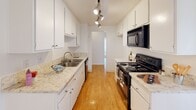 Located at Casa de Oro on Ocean Ave in Torrance, California, this single-floor residence offers a clean, functional layout with a bright and neutral interior throughout. The galley-style kitchen is thoughtfully designed with white cabinetry, granite-style countertops, a double-basin sink, black appliances including a range and over-the-range microwave, and warm wood-look flooring underfoot. Track lighting illuminates the workspace, adding a modern touch to the efficient layout. Adjacent to the kitchen, a dining or flex area features the same wood-look flooring, vertical blinds, and a ceiling fan, creating an airy and comfortable setting. The living area is carpeted in warm beige tones with a textured ceiling and large sliding glass doors that open to an outdoor balcony, allowing natural light to fill the space. The bedrooms are generously sized, finished with plush carpet, white walls, textured ceilings, and vertical blinds that soften incoming light. Bathrooms are well-appointed with wood-look flooring, granite-style vanity countertops, large mirrors, and sliding glass shower/tub enclosures with chrome hardware. The overall aesthetic is clean, light, and move-in ready, offering a comfortable living environment in a convenient South Bay location.