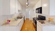 Located at Casa de Oro on Ocean Ave in Torrance, California, this single-floor residence offers a clean, functional layout with a bright and neutral interior throughout. The galley-style kitchen is thoughtfully designed with white cabinetry, granite-style countertops, a double-basin sink, black appliances including a range and over-the-range microwave, and warm wood-look flooring underfoot. Track lighting illuminates the workspace, adding a modern touch to the efficient layout. Adjacent to the kitchen, a dining or flex area features the same wood-look flooring, vertical blinds, and a ceiling fan, creating an airy and comfortable setting. The living area is carpeted in warm beige tones with a textured ceiling and large sliding glass doors that open to an outdoor balcony, allowing natural light to fill the space. The bedrooms are generously sized, finished with plush carpet, white walls, textured ceilings, and vertical blinds that soften incoming light. Bathrooms are well-appointed with wood-look flooring, granite-style vanity countertops, large mirrors, and sliding glass shower/tub enclosures with chrome hardware. The overall aesthetic is clean, light, and move-in ready, offering a comfortable living environment in a convenient South Bay location.