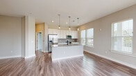 Located at 1841 Dusty Miller Lane in Wilmington, NC, this well-appointed single-floor residence offers a thoughtfully designed layout with modern finishes throughout. The open-concept kitchen serves as the heart of the home, featuring crisp white shaker cabinetry, granite countertops, a classic subway tile backsplash, and a full suite of stainless steel appliances including a refrigerator with ice maker, electric range, over-the-range microwave, and dishwasher. A central island with pendant lighting above provides additional prep space and casual seating, while large windows allow generous natural light to fill the area. Durable wood-look flooring runs through the main living areas, complementing the neutral color palette that carries throughout the home. The bedrooms are carpeted for comfort and each features windows with exterior views, with at least one room offering a ceiling fan. The bathrooms are finished with granite-topped vanities and wood-look flooring; one features a dual-sink vanity with framed mirrors and a tub-shower combination, while another offers a glass-enclosed shower. A dedicated in-unit laundry closet houses a full-size washer and dryer, adding everyday convenience to this well-rounded Wilmington residence.